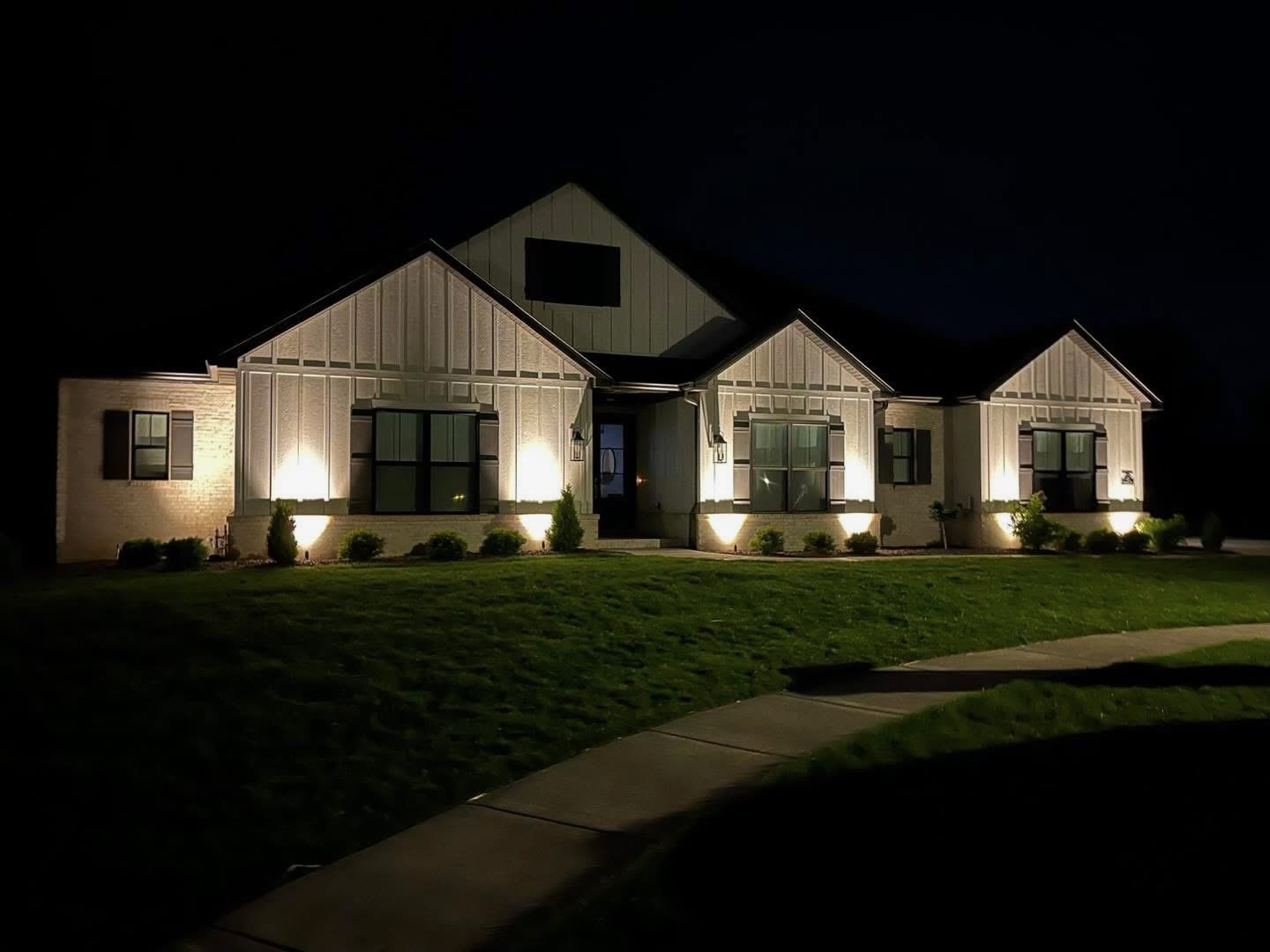 Modern farmhouse with professional landscape uplighting at night