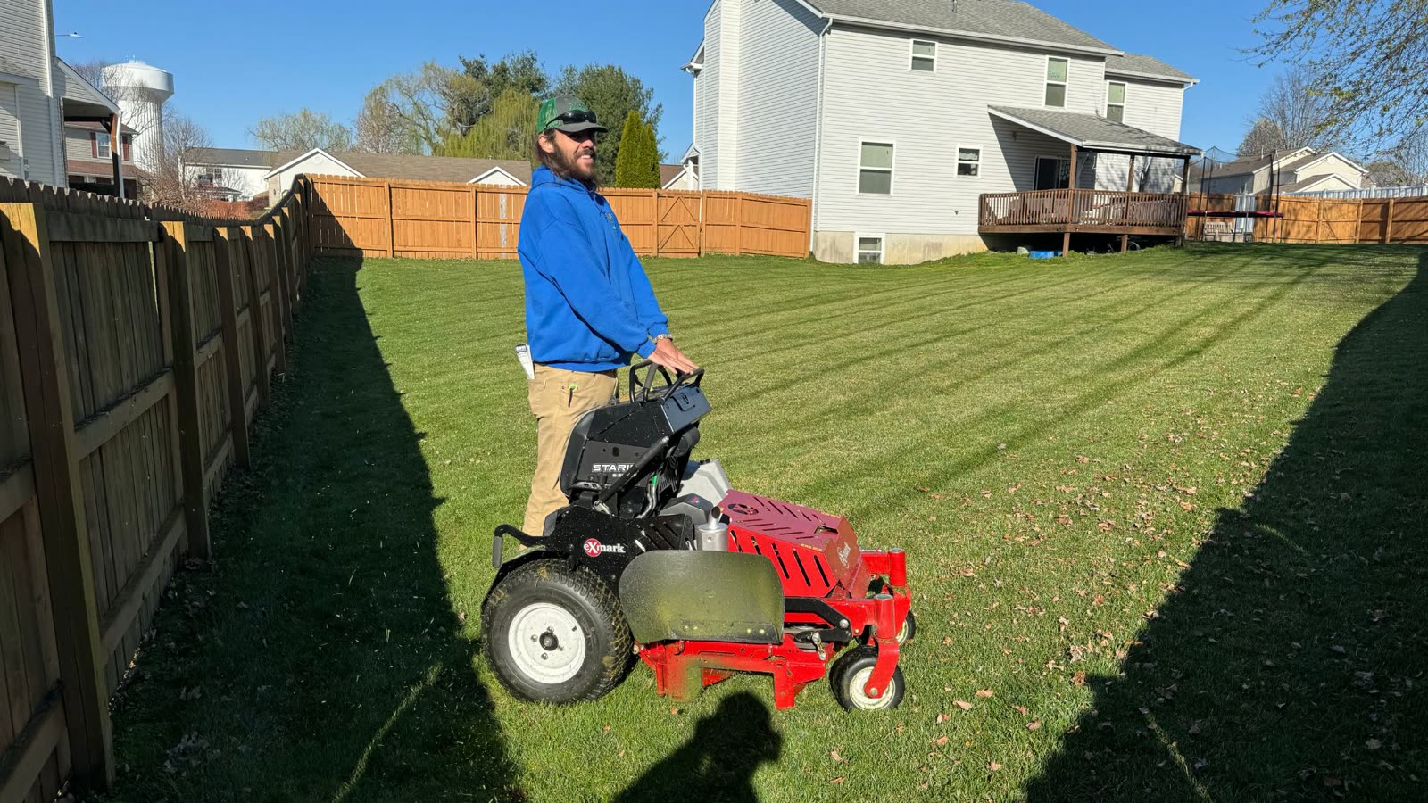 Superior Outdoor operating a stand-on mower on a striped lawn